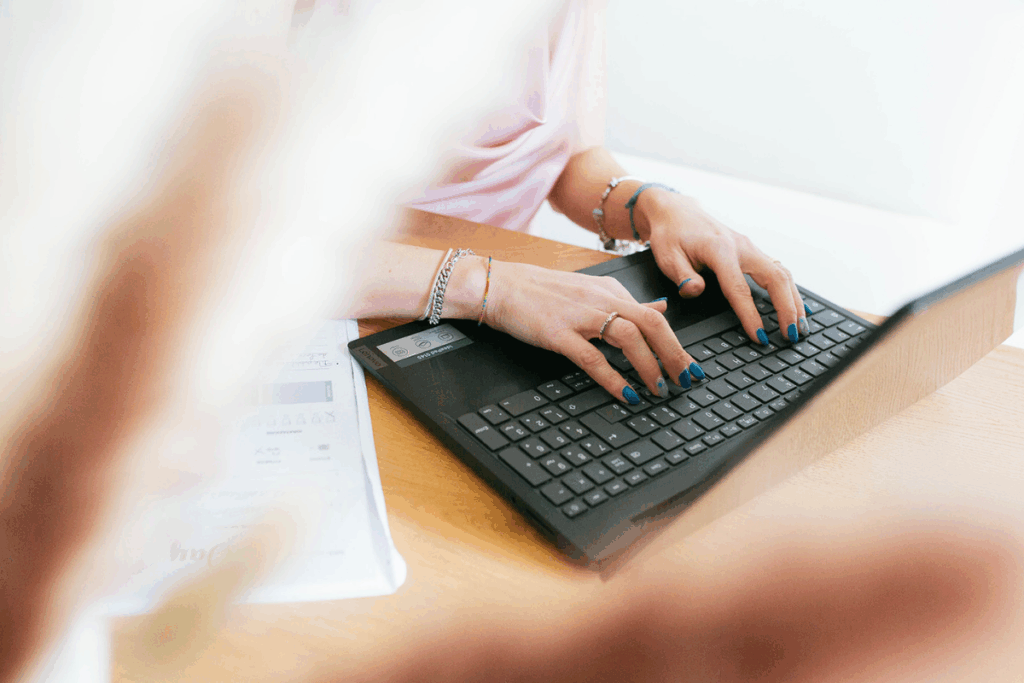 si vedono le mani di una ragazza che scrivono al pc
